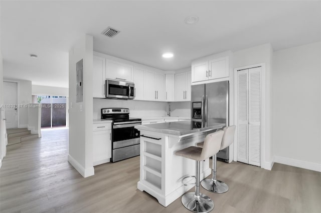 6514 SW 128th Pl Unit 6514, Miami, FL 33183 - kitchen with appliances with stainless steel finishes, light wood-type flooring, a kitchen bar, white cabinetry, and recessed lighting