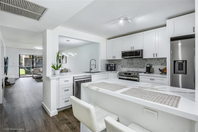 37 Seville Cir Unit 1-50, Davie, FL 33324 - kitchen with stainless steel appliances, tasteful backsplash, a peninsula, and white cabinetry