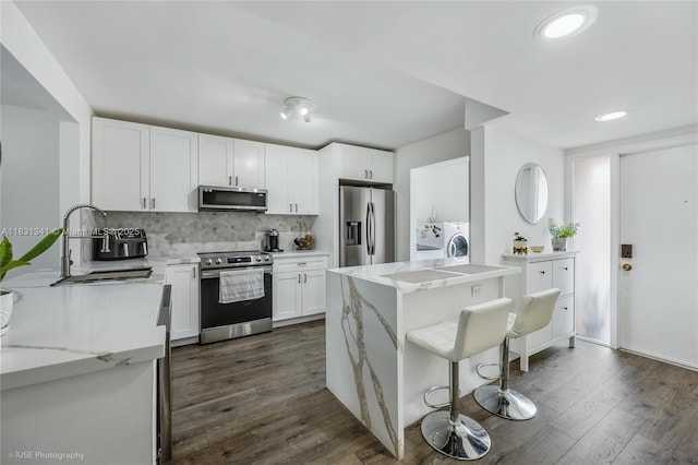 37 Seville Cir Unit 1-50, Davie, FL 33324 - kitchen with appliances with stainless steel finishes, washing machine and clothes dryer, light stone counters, tasteful backsplash, and white cabinetry