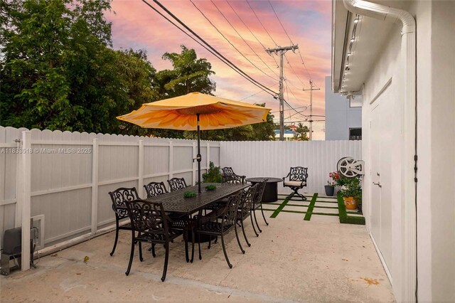 240 NE 97th St, Miami Shores, FL 33138 - patio terrace at dusk featuring a fenced backyard, a patio area, and outdoor dining space