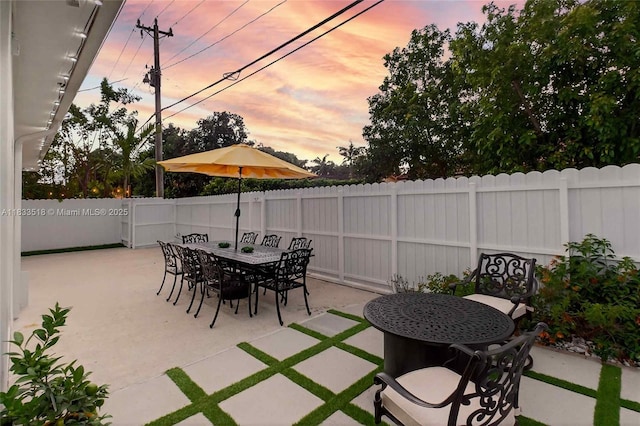 240 NE 97th St, Miami Shores, FL 33138 - patio terrace at dusk featuring a patio area, a fenced backyard, and outdoor dining area