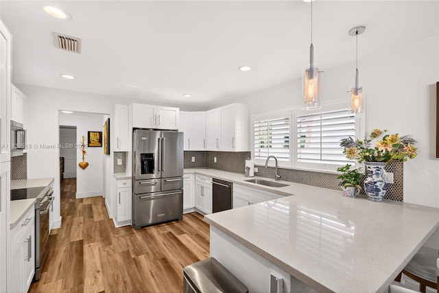 240 NE 97th St, Miami Shores, FL 33138 - kitchen with high end appliances, a peninsula, a breakfast bar area, white cabinetry, and recessed lighting
