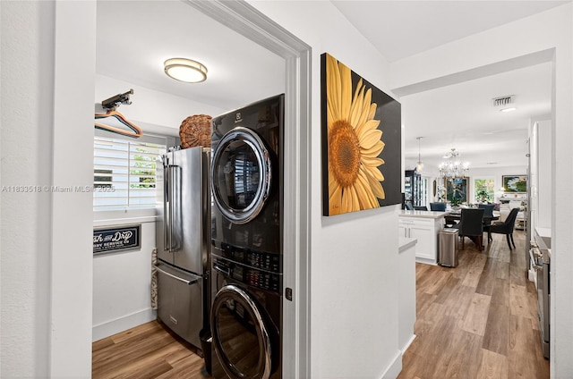 240 NE 97th St, Miami Shores, FL 33138 - washroom with estacked washer and dryer, a chandelier, and light wood finished floors