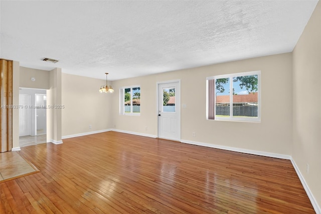 4061 Nova Ln, Lake Worth, FL 33462 - empty room featuring a chandelier, light wood-style flooring, healthy amount of natural light, and a textured ceiling