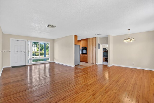 4061 Nova Ln, Lake Worth, FL 33462 - unfurnished living room with a chandelier, light wood finished floors, and a textured ceiling