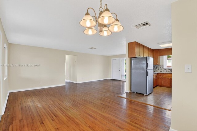 4061 Nova Ln, Lake Worth, FL 33462 - kitchen with freestanding refrigerator, a chandelier, dark wood-style floors, tasteful backsplash, and brown cabinetry