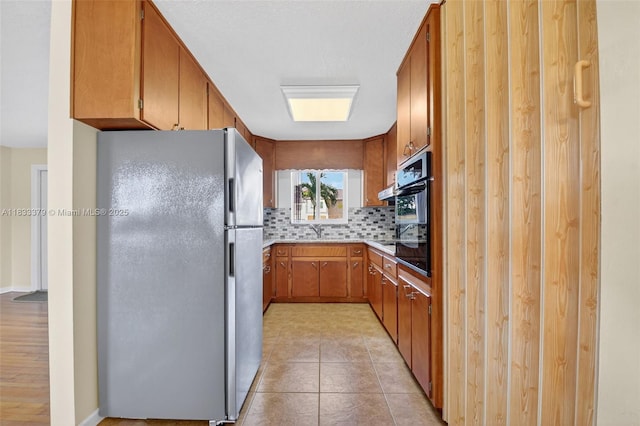 4061 Nova Ln, Lake Worth, FL 33462 - kitchen featuring freestanding refrigerator, oven, tasteful backsplash, brown cabinetry, and light countertops