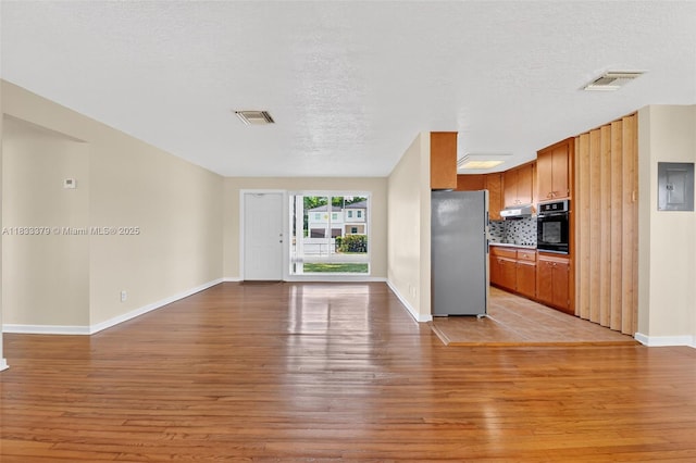 4061 Nova Ln, Lake Worth, FL 33462 - kitchen with freestanding refrigerator, black oven, open floor plan, electric panel, and light wood-style floors
