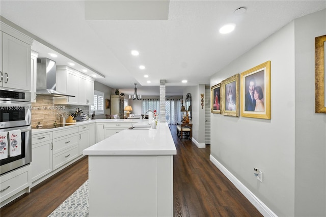 1651 SW 127th Ave Unit 301A, Pembroke Pines, FL 33027 - kitchen with wall chimney exhaust hood, a peninsula, stainless steel double oven, recessed lighting, and tasteful backsplash
