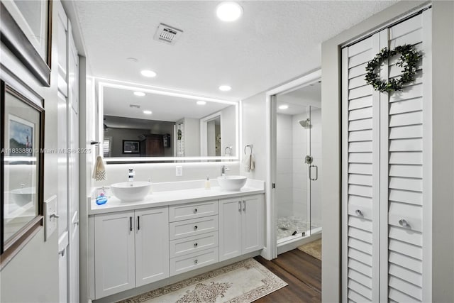 1651 SW 127th Ave Unit 301A, Pembroke Pines, FL 33027 - full bathroom featuring double vanity, a shower stall, wood finished floors, a textured ceiling, and a closet