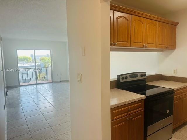 3181 SW 13th St Unit 307, Miami, FL 33145 - kitchen featuring stainless steel range with electric stovetop, light tile patterned floors, open floor plan, and brown cabinets