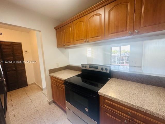 3181 SW 13th St Unit 307, Miami, FL 33145 - kitchen featuring stainless steel electric range oven, brown cabinetry, and light tile patterned floors