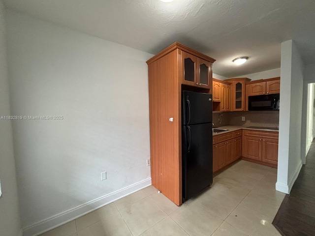 1860 Venice Park Dr Unit 110, North Miami, FL 33181 - kitchen with black appliances, glass insert cabinets, light tile patterned flooring, brown cabinetry, and light countertops