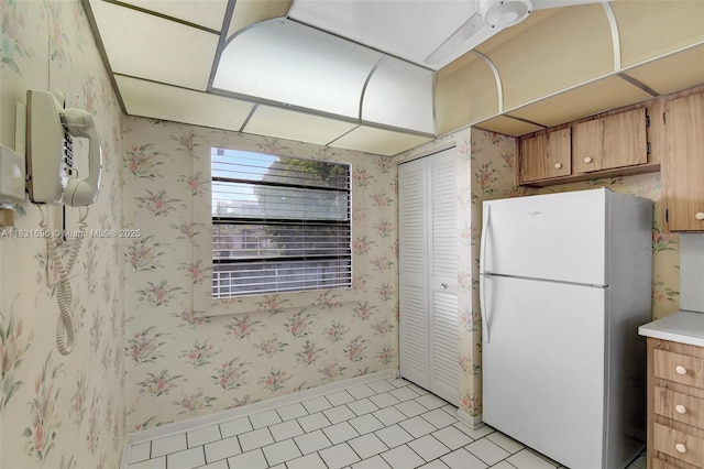 1001 Colony Point Cir Unit 220, Pembroke Pines, FL 33026 - kitchen with freestanding refrigerator, wallpapered walls, light countertops, brown cabinetry, and light tile patterned flooring