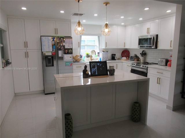 6910 SW 26th Ct, Miramar, FL 33023 - kitchen featuring stainless steel appliances, backsplash, white cabinetry, a center island, and light countertops