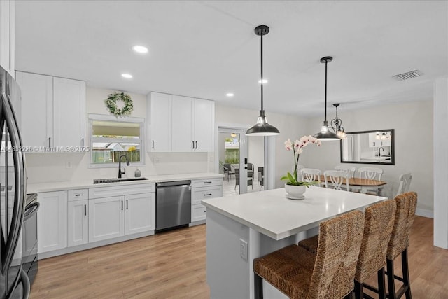 9360 SW 185th St, Cutler Bay, FL 33157 - kitchen with stainless steel dishwasher, a breakfast bar area, a center island, white cabinetry, and light wood-style flooring