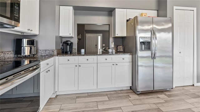 1226 SW Curry St, Port St Lucie, FL 34983 - kitchen with stainless steel appliances, white cabinetry, dark stone counters, and wood tiled floors