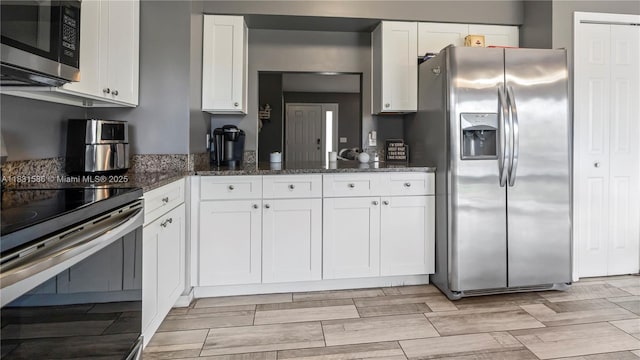 1226 SW Curry St, Port St Lucie, FL 34983 - kitchen featuring appliances with stainless steel finishes, white cabinets, and dark stone counters