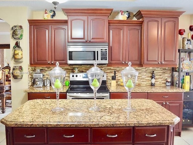 15601 SW 31st Ln, Miami, FL 33185 - kitchen with stainless steel appliances, reddish brown cabinets, light stone counters, and decorative backsplash