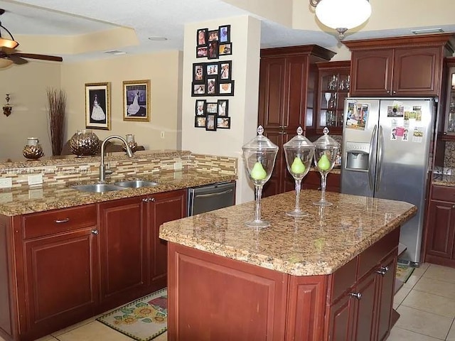 15601 SW 31st Ln, Miami, FL 33185 - kitchen featuring stainless steel appliances, an island with sink, reddish brown cabinets, ceiling fan, and light stone counters
