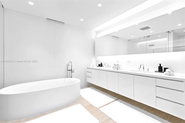 9001 Collins Ave Unit S-305, Surfside, FL 33154 - bathroom featuring double vanity, a freestanding bath, a stall shower, recessed lighting, and wood finished floors