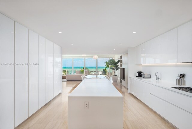 9001 Collins Ave Unit S-305, Surfside, FL 33154 - kitchen featuring modern cabinets, a kitchen island, stainless steel gas stovetop, white cabinetry, and a wall of windows