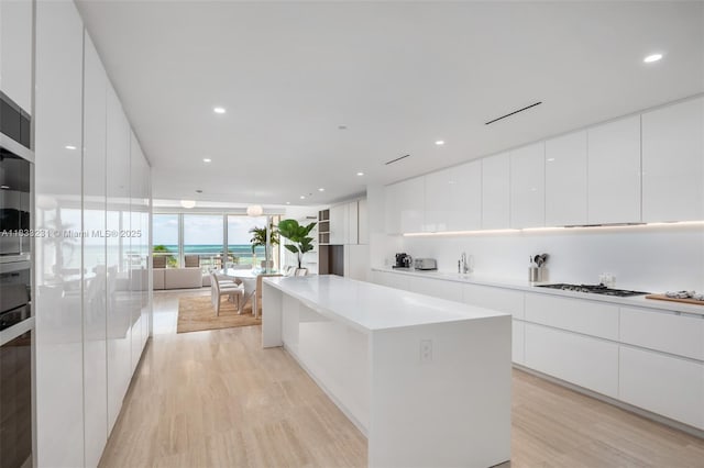 9001 Collins Ave Unit S-305, Surfside, FL 33154 - kitchen featuring modern cabinets, light wood finished floors, a kitchen island, white cabinetry, and gas cooktop