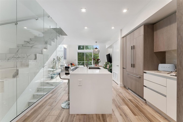 455 NE 39th St Unit 105, Miami, FL 33137 - kitchen featuring modern cabinets, light countertops, light wood-style flooring, a center island with sink, and recessed lighting
