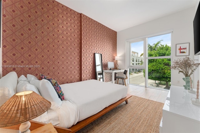 455 NE 39th St Unit 105, Miami, FL 33137 - bedroom featuring wallpapered walls, access to outside, wood finished floors, and an accent wall