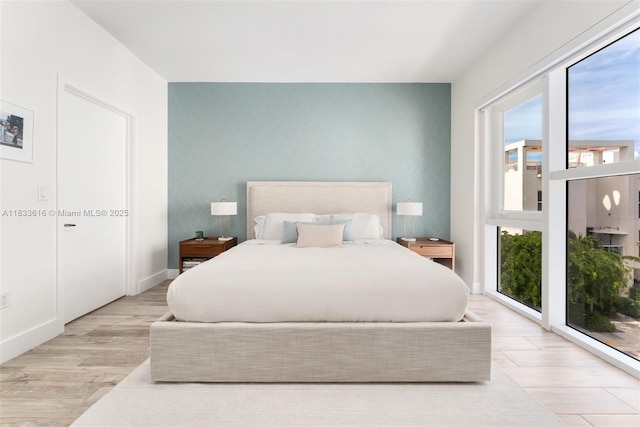 455 NE 39th St Unit 105, Miami, FL 33137 - bedroom featuring an accent wall, multiple windows, wood finished floors, and access to exterior