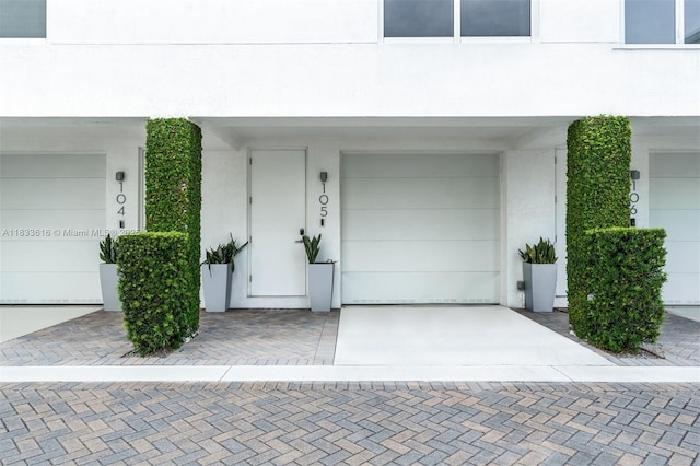 455 NE 39th St Unit 105, Miami, FL 33137 - entrance to property with a garage, concrete driveway, and stucco siding