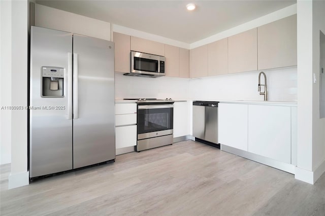 19380 NE 26th Ave Unit 304, Miami, FL 33180 - kitchen featuring appliances with stainless steel finishes, light wood-style flooring, light countertops, tasteful backsplash, and cream cabinetry