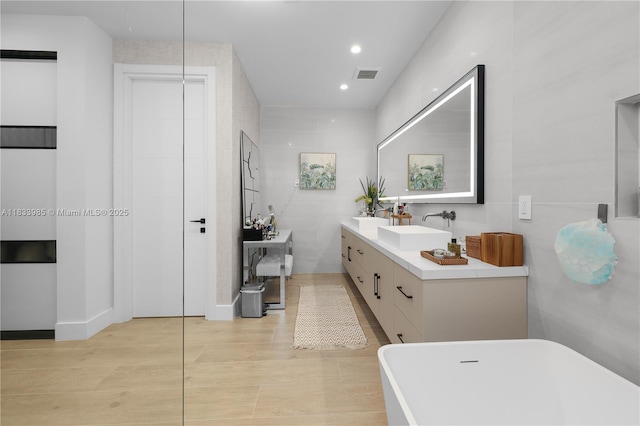 436 NE 10th Ave, Fort Lauderdale, FL 33301 - full bathroom featuring a freestanding bath, double vanity, wood finished floors, and recessed lighting