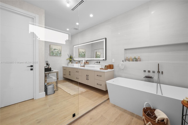 436 NE 10th Ave, Fort Lauderdale, FL 33301 - full bathroom with double vanity, a soaking tub, recessed lighting, and wood finished floors