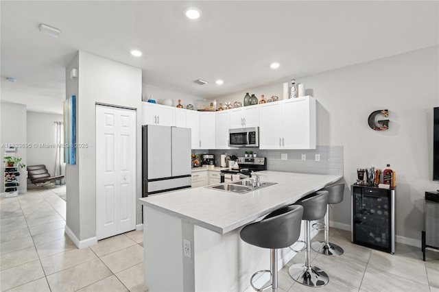 10468 W 33rd Ln, Hialeah, FL 33018 - kitchen with appliances with stainless steel finishes, beverage cooler, a peninsula, light countertops, and a kitchen bar
