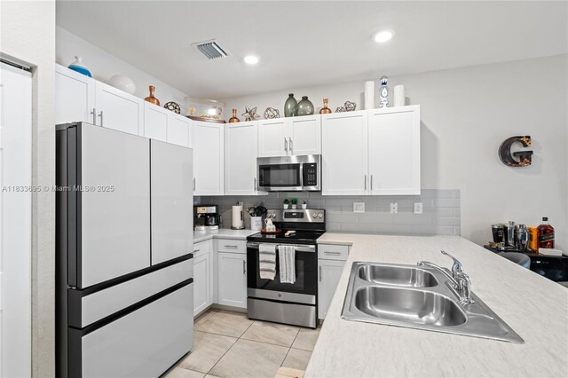 10468 W 33rd Ln, Hialeah, FL 33018 - kitchen featuring stainless steel appliances, white cabinets, light countertops, backsplash, and light tile patterned floors