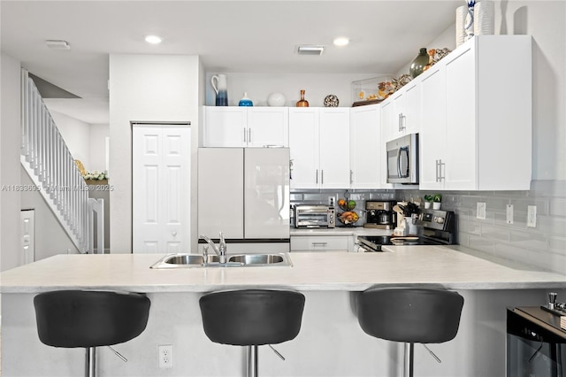 10468 W 33rd Ln, Hialeah, FL 33018 - kitchen featuring stainless steel appliances, light countertops, a kitchen breakfast bar, a peninsula, and backsplash