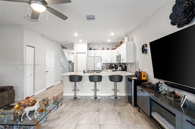 10468 W 33rd Ln, Hialeah, FL 33018 - kitchen featuring white refrigerator, a peninsula, decorative backsplash, a breakfast bar area, and light tile patterned floors