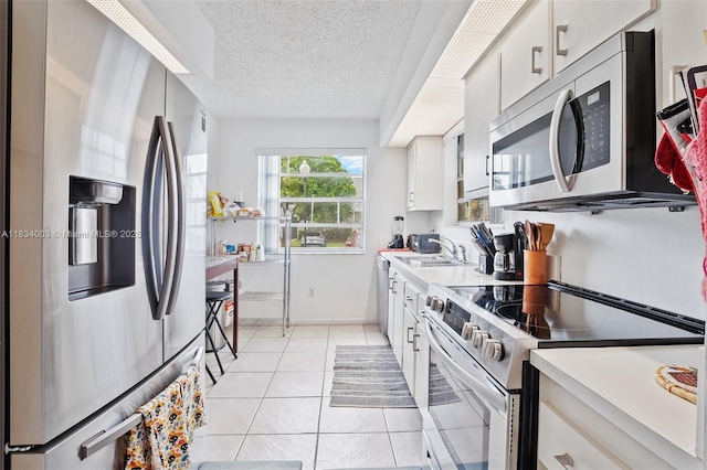 2657 SE 19th Ct Unit 103-E, Homestead, FL 33035 - kitchen featuring stainless steel appliances, white cabinetry, light countertops, light tile patterned flooring, and a textured ceiling