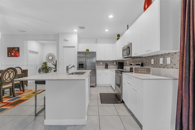 2409 NW 131st Cir, Miami, FL 33167 - kitchen featuring appliances with stainless steel finishes, decorative backsplash, a kitchen bar, light tile patterned floors, and recessed lighting
