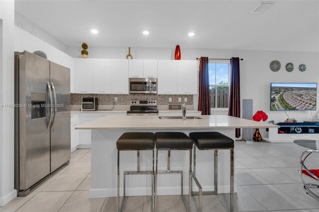 2409 NW 131st Cir, Miami, FL 33167 - kitchen featuring stainless steel appliances, light countertops, a kitchen bar, decorative backsplash, and white cabinetry