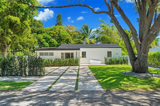 1003 NE 115th St, Biscayne Park, FL 33161 - view of front of home with stucco siding, a front yard, and driveway