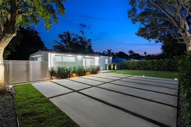 1003 NE 115th St, Biscayne Park, FL 33161 - back of house at dusk featuring stucco siding and a gate