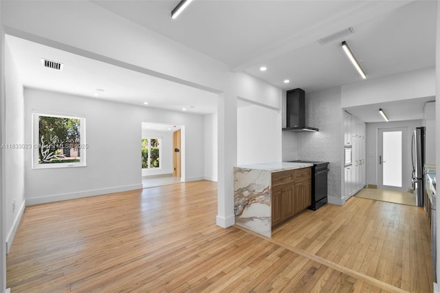 1003 NE 115th St, Biscayne Park, FL 33161 - kitchen featuring black / electric stove, wall chimney exhaust hood, light wood finished floors, freestanding refrigerator, and recessed lighting