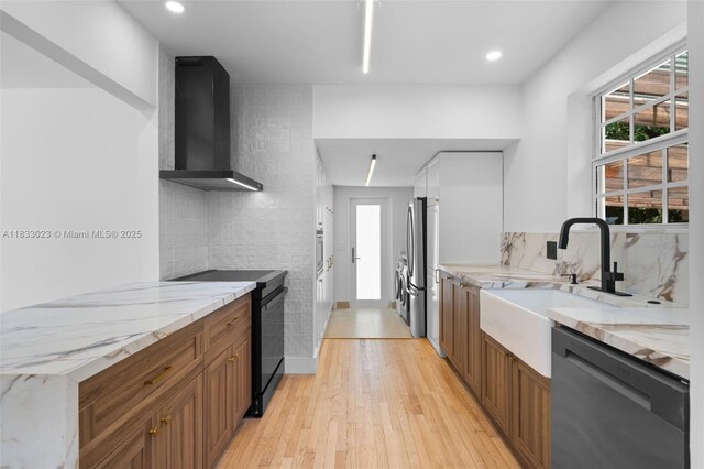 1003 NE 115th St, Biscayne Park, FL 33161 - kitchen with appliances with stainless steel finishes, wall chimney range hood, light wood finished floors, light stone counters, and brown cabinets