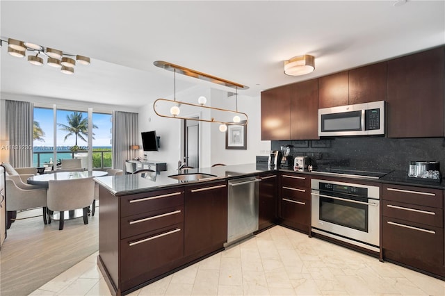 4391 Collins Ave Unit 623, Miami Beach, FL 33140 - kitchen with stainless steel appliances, dark countertops, a peninsula, and decorative backsplash