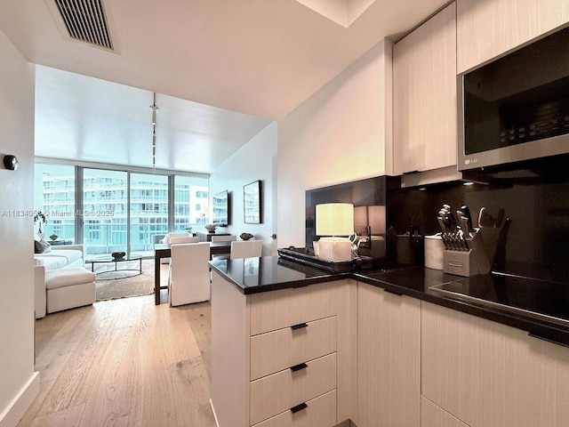 1331 Brickell Bay Dr Unit 506, Miami, FL 33131 - kitchen featuring stainless steel microwave, expansive windows, a peninsula, open floor plan, and light wood-style floors
