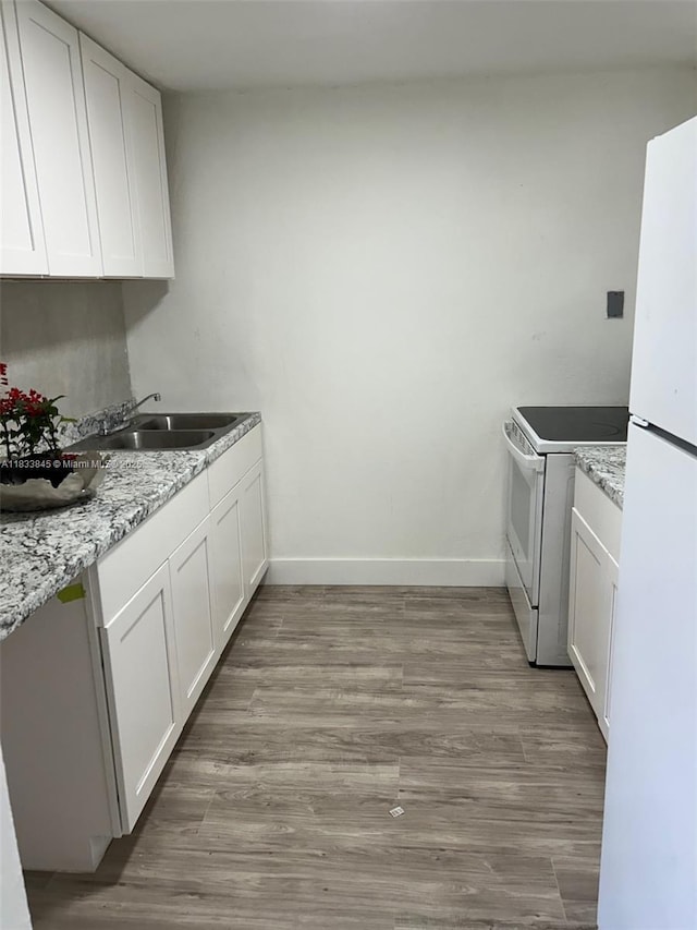 22020 SW 115th Ct, Miami, FL 33170 - kitchen featuring white appliances, wood finished floors, white cabinets, and light stone countertops