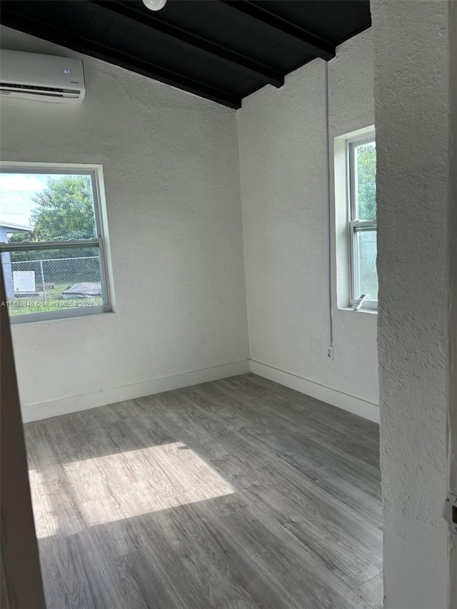 22020 SW 115th Ct, Miami, FL 33170 - empty room with a textured wall, an AC wall unit, beam ceiling, wood finished floors, and plenty of natural light