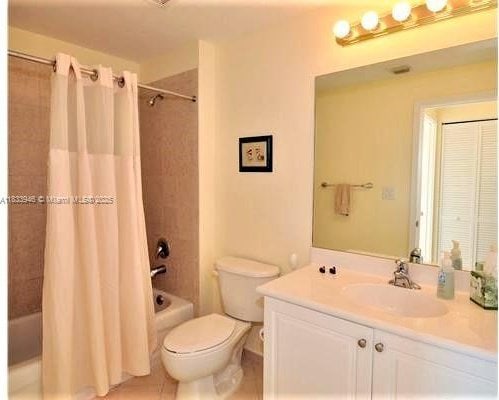 9021 SW 94th St Unit 606, Miami, FL 33176 - bathroom featuring vanity, shower / bathtub combination with curtain, and tile patterned flooring